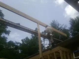 Carpenter setting a ridge beam over a new addition frame — Ice Dam Removal by Roofing Brothers in Lamar