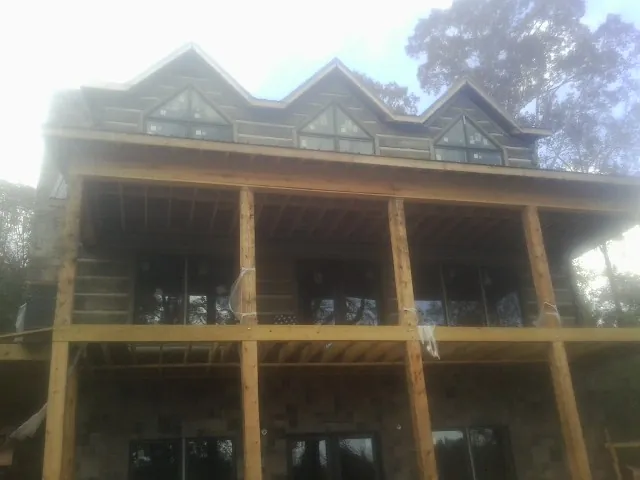 Dormers and porch framing on a large log home under construction — Roof Coating work by our crew in Lamar